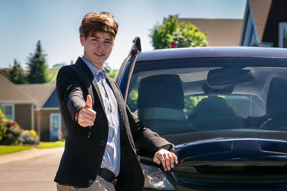 happy college student standing beside his car - back to college car shipping service